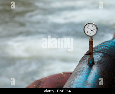 Barometer auf einem blauen rostige Wasser Rohr über einen Fluss in der Stadt Stockfoto