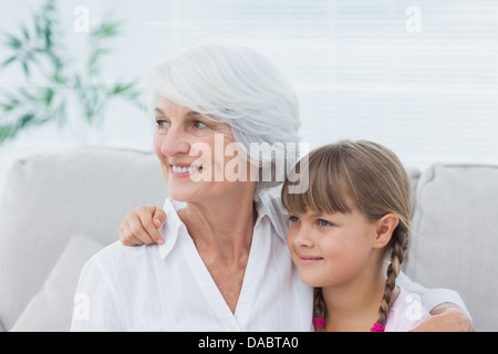 Niedliche Mädchen und Großmutter sitzen auf der couch Stockfoto