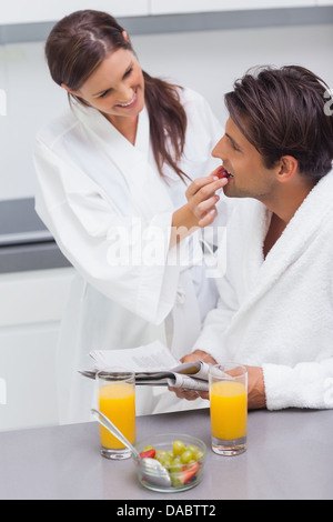 Frau trägt Bademantel Fütterung ihr Ehemann Erdbeere Stockfoto