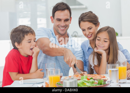 Man schneidet eine Pizza für seine Familie Stockfoto