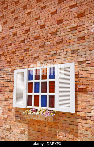 Weißes Fenster mit Blumentöpfen auf der gemauerten Wand Hintergrund. Stockfoto