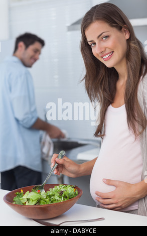 Schwangere Frau bereitet einen Salat in der Küche Stockfoto