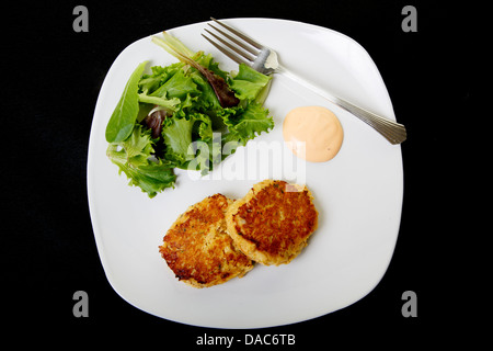 Frische Krabbenkuchen auf einem weißen Teller mit Sauce und einen frischen Salat der grünen Feld Stockfoto