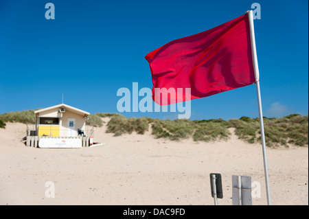 Eine rote Flagge vor Bohnenstroh Rettungsschwimmer am Strand Konstantin Bay Cornwall UK Stockfoto