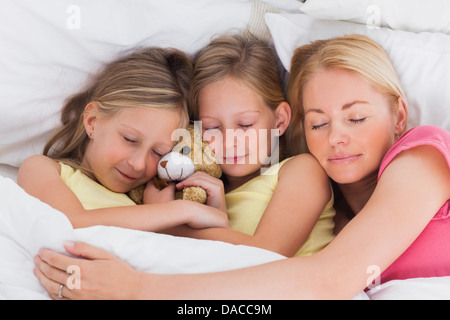 Frau schläft im Bett mit ihren süßen Kindern Stockfoto