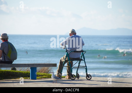 Mann saß mit Blick auf das Meer an einem warmen sonnigen Tag. Stockfoto