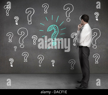 Geschäftsmann, Blick auf Zeichnungen von Fragezeichen Stockfoto