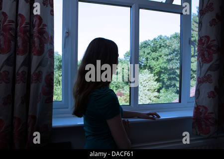 Ein junges Mädchen, Blick aus dem Fenster. Hinten/Seitenansicht. Stockfoto