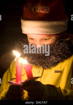 Ein kleines Mädchen beobachtet ihre Kerze an die Alte Foersterei in Berlin, Deutschland, 23. Dezember 2011. Etwa 17 000 Menschen nahmen an der jährlichen Weihnachten singen von Weihnachtsliedern Veranstaltung von der Fußball-Club 1. FC Union Berlin. Foto: Britta Pedersen Stockfoto