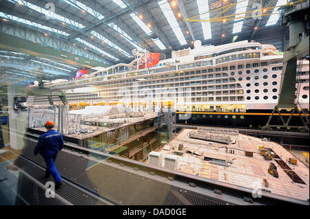 Ein Arbeiter auf der Meyer Werft Spaziergänge entlang das Kreuzfahrtschiff "Disney Fantasy" im Bau in Papenburg, Deutschland, 28. Dezember 2011. Der 300 m-Liner am 7. Januar 2012 abgedockt werden soll und zwei Wochen später auf der Ostsee übertragen. Die "Tage der Region" vom 27. bis 29. Dezember 2011 bot ihren Besuchern die Möglichkeit, die Papenburg-Region besser kennenlernen. P Stockfoto