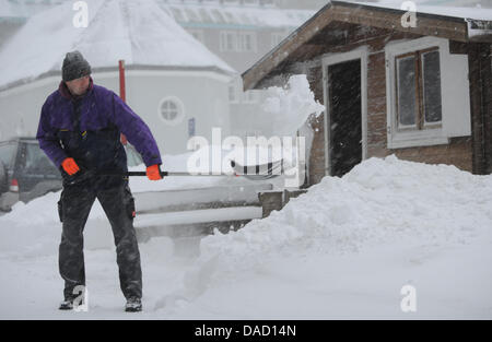 Ein Mann schaufelt Schnee vor einem Haus in Feldberg im Schwarzwald, Deutschland, 30. Dezember 2011. Schneefall und Schneeverwehungen halten Verkehr im Schwarzwald. Foto: Patrick Seeger Stockfoto