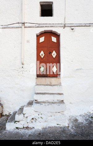Rote Tür mit weißer Diamant-Muster in weiß getünchten Mauer, mittelalterliche Altstadt, Ostuni, Apulien, Süditalien Stockfoto