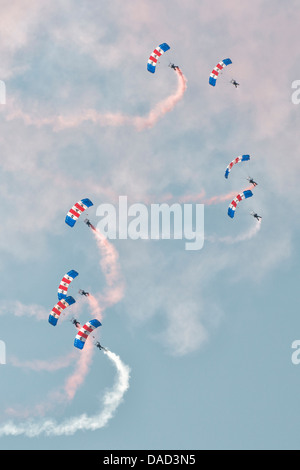 Fallschirmspringer aus der Royal Air Force Falcons anzeigen Team füllen den Himmel mit ihren bunten Fallschirm Verdecke und Rauch Wanderwege Stockfoto