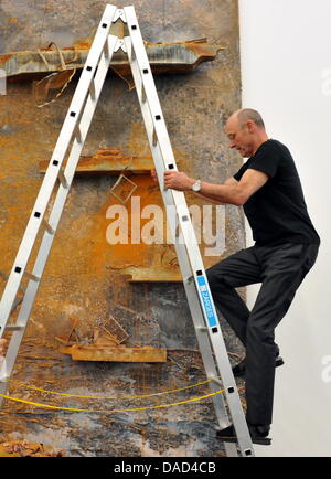 Der Künstler Anselm Kiefer klettert eine Leiter vor seinem Bild "Reise zum Ende der Nacht" (Voyage au Bout De La Nuit) in Baden-Baden, Deutschland, 5. Oktober 2011. Kiefer, selbst Schliff den letzten auf die Positionierung des dreidimensionalen Bildes.  Die große Ausstellung trägt den Titel "Anselm Kiefer. Ausgewählte Werke aus der Sammlung Grothe ".  Großformatige Werke von der deutschen Stockfoto