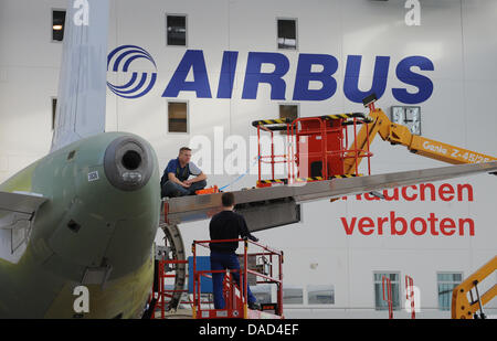 Datei - eine Archiv Bild datiert 6. Februar 2009 zeigt Mitarbeiter stehen neben einem Airbus in der Endmontage-Halle an das Airbus-Werk in Hamburg-Finkenwerder, Deutschland. In der Handelskonflikt an Flugzeughersteller Airbus bemühen sich beide Parteien, einen Kompromiss zu erzielen. Auf Mittwoch, 5. Oktober 2011, Vertreter von Airbus, der Gewerkschaft IG Metall und dem Betriebsrat Stockfoto