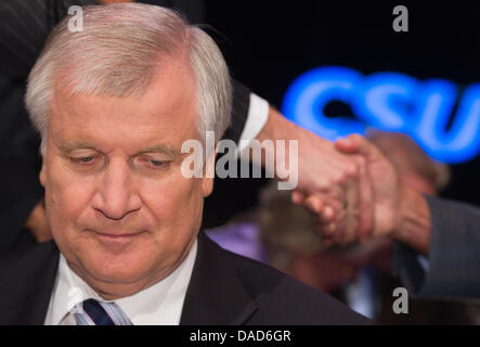 Vorsitzender der CSU (christlich soziale Union Bayern) Horst Seehofer sitzt vor der der Partei-Logo während dem CSU-Parteitag in Nürnberg, Bayern, Deutschland, 08 Oktober 2011. Im Vordergrund ist eine Flagge geschwenkt wird. Von 07 bis 08 Oktober findet die jährliche CSU-Parteitag in Nürnberg statt. Foto: PETER KNEFFEL Stockfoto