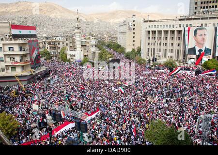 Tausende von Syrer Welle Nationalflaggen sowie chinesische und russische Fahnen während einer regierungsnahen Kundgebung auf Saba Bahrat Platz in Damaskus, Syrien, am 12. Oktober 2011. Laut Medienquellen sammelten sich Tausende von Syrer zur Unterstützung des Regimes des syrischen Präsidenten Bashar al-Assad, und Anerkennung nach Russland und China für ihre unterstützende Haltung für Syrien. Am 04 Oktober Stockfoto