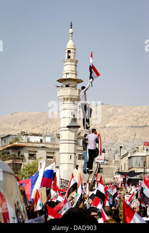 Tausende von Syrer Welle Nationalflaggen sowie chinesische und russische Fahnen während einer regierungsnahen Kundgebung auf Saba Bahrat Platz in Damaskus, Syrien, am 12. Oktober 2011. Laut Medienquellen sammelten sich Tausende von Syrer zur Unterstützung des Regimes des syrischen Präsidenten Bashar al-Assad, und Anerkennung nach Russland und China für ihre unterstützende Haltung für Syrien. Am 04 Oktober Stockfoto