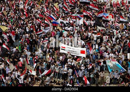 Tausende von Syrer Welle Nationalflaggen sowie chinesische und russische Fahnen während einer regierungsnahen Kundgebung auf Saba Bahrat Platz in Damaskus, Syrien, am 12. Oktober 2011. Laut Medienquellen sammelten sich Tausende von Syrer zur Unterstützung des Regimes des syrischen Präsidenten Bashar al-Assad, und Anerkennung nach Russland und China für ihre unterstützende Haltung für Syrien. Am 04 Oktober Stockfoto