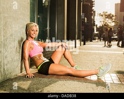 Weibliche Läufer auf Bürgersteig sitzen Stockfoto