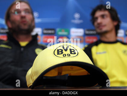 Headcoach von Borussia Dortmund Jürgen Klopp und Player Mats Hummels sitzen hinter einer Kappe mit einem Logo des Bundesligisten bei einer Pressekonferenz im Vorfeld der UEFA Champions League-Spiel zwischen Olympiakos Piräus und Borussia Dortmund am 19. Oktober 2011 im Karaiskakis-Stadion in Piräus, Griechenland, 18. Oktober 2011. Foto: Friso Gentsch Stockfoto