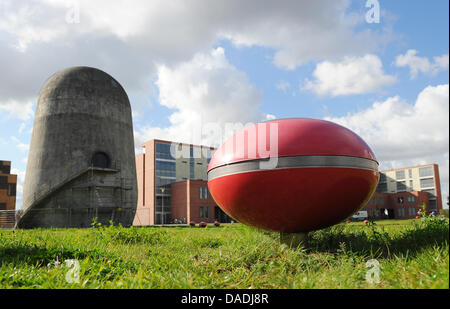 Ein rotes elliptisches Objekt, das die Soundinstallation Luft getragen gehört liegt vor der Trudelturm (L) an der Aerodynamik-Park auf dem Campus der Humboldt-Universität Berlin in Berlin-Adlershof, Deutschland, 13. Oktober 2011. Der Trudelturm für wissenschaftliche Zwecke in den 1930er Jahren errichtet und ist heute ein Denkmal, das werden Besucher über die Geschichte der spezifischen erinnert Stockfoto