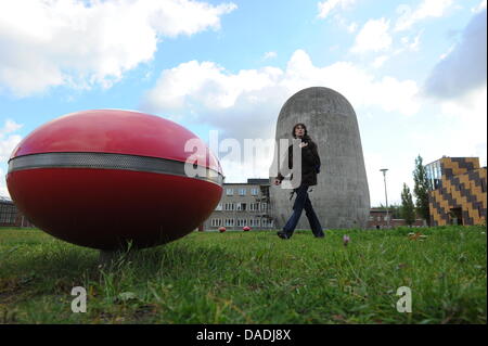 Ein rotes elliptisches Objekt, das die Soundinstallation Luft getragen gehört liegt vor der Trudelturm (L) an der Aerodynamik-Park auf dem Campus der Humboldt-Universität Berlin in Berlin-Adlershof, Deutschland, 13. Oktober 2011. Der Trudelturm für wissenschaftliche Zwecke in den 1930er Jahren errichtet und ist heute ein Denkmal, das werden Besucher über die Geschichte der spezifischen erinnert Stockfoto