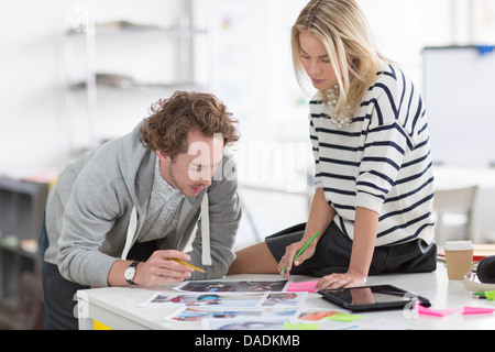 Kolleginnen und Kollegen diskutieren Fotografien auf Schreibtisch im Kreativbüro Stockfoto