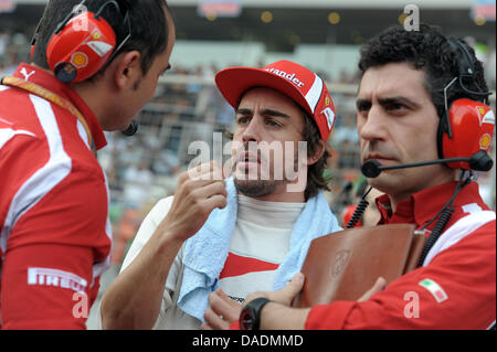 Spanische Formel1-Fahrer Fernando Alonso (C) von Ferrari spricht mit seinen Ingenieuren im Raster kurz vor dem Start des Rennens auf dem Buddh International Circuit, Greater Noida, Indien, 30. Oktober 2011. Die erste Formel 1 Grand Prix von Indien statt findet am 30. Oktober 2011. Foto: David Ebener Dpa +++(c) Dpa - Bildfunk +++ Stockfoto