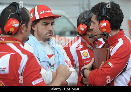 Spanische Formel1-Fahrer Fernando Alonso (C) von Ferrari spricht mit seinen Ingenieuren im Raster kurz vor dem Start des Rennens auf dem Buddh International Circuit, Greater Noida, Indien, 30. Oktober 2011. Die erste Formel 1 Grand Prix von Indien statt findet am 30. Oktober 2011. Foto: David Ebener dpa Stockfoto