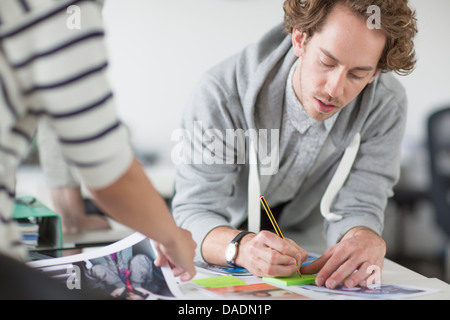 Junger Mann Notizen auf Schreibtisch im Kreativbüro Stockfoto