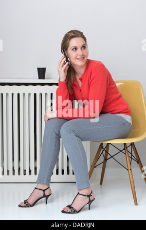 Junge Frau auf Stuhl mit Handy Stockfoto
