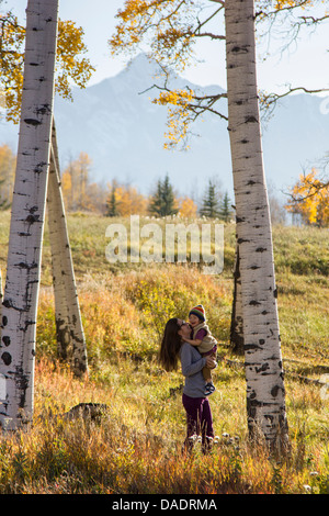 Mutter Holding Kleinkind unter Silber Birken Stockfoto