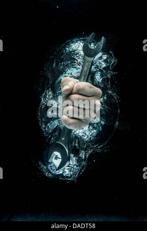 Männliche Hand greifen Schraubenschlüssel unter Wasser Stockfoto