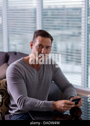 Mitte erwachsener Mann sitzen und halten Handys Stockfoto