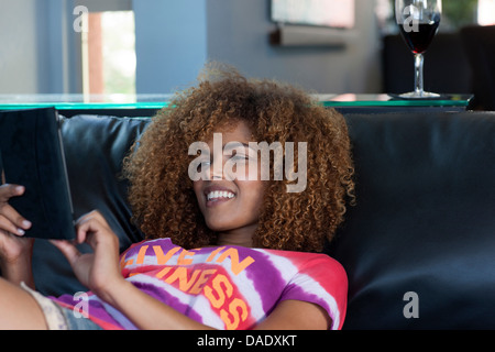 Mitte entspannend auf Sofa mit elektronischen Buch, Erwachsene Frau lächelnd Stockfoto