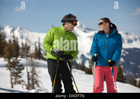 Junge Frau und reifer Mann in Skibekleidung holding Skistöcke Stockfoto