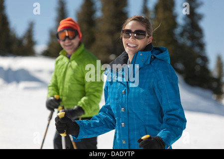 Junge Frau in Skibekleidung mit Skistöcken, Porträt Stockfoto