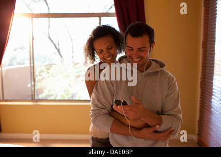 Junges Paar anhören von MP3-Player im Hotel Zimmer, lächelnd Stockfoto