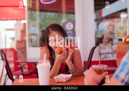 Junge Frau Essen Hotdog im Diner, Porträt Stockfoto
