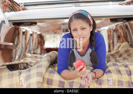 Junge Frau liegt im Wohnmobil, Lächeln Stockfoto
