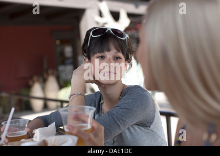 Freundinnen, die Getränke im Café im Freien, Lächeln Stockfoto