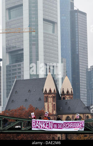 Ein Banner "Banken in Die Schranken" zu sagen (zurückhalten Banken) ist eingerichtet auf der Brücke Eiserner Steg in Frankfurt Am Main, Deutschland, 10. November 2011. Eine Koalition von Organisationen und Verbänden lief eine Menschenkette im Frankfurter Bankenviertel und Berlins Regierungsbezirk auf Nachfrage paradigmatische Folgen für die aktuelle Finanzkrise am 12. November 2011. Foto: M Stockfoto