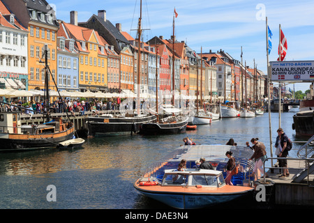 Touristen auf Tour Kanalboot mit alten Boote vertäut vor bunten Gebäuden im Hafen von Nyhavn Kopenhagen Seeland Dänemark Stockfoto