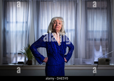 Ältere Frau im blauen Kleid mit Händen auf den Hüften Stockfoto