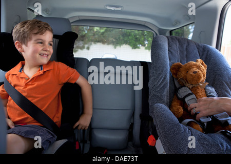 Junge im Kindersitz im Auto mit Teddybär Stockfoto