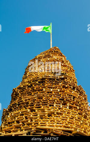 Newtownabbey, Nordirland, Vereinigtes Königreich. 11. Juli 2013 Die irische Dreifarbflagge fliegt auf einem loyalen Lagerfeuer, das verbrannt werden kann. Stockfoto