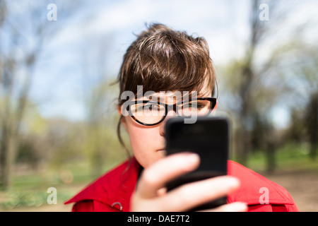 Frau im Stadtpark Blick auf smartphone Stockfoto