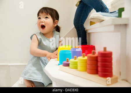 Weiblichen Kleinkind spielen mit Spielzeug auf Treppe Stockfoto