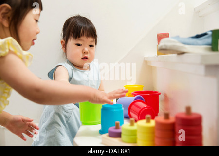 Zwei junge Schwestern spielen mit Spielzeug auf Treppe Stockfoto